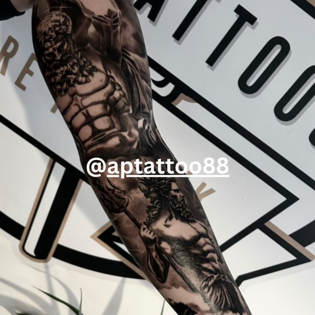 Tattooed arm with detailed black and white designs against a tattoo studio background.