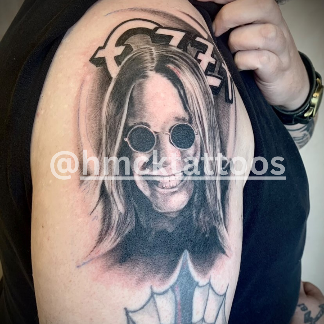 Tattoo of a person with sunglasses on an arm, with 'hmck tattoos' branding.