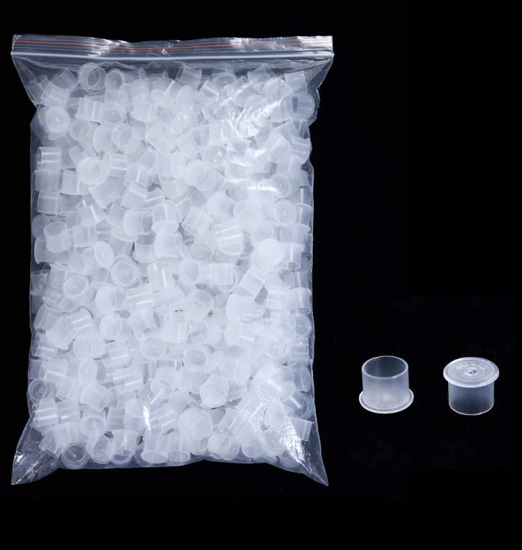 Bag of clear disposable plastic tattoo ink cups with two individual cups on a black background