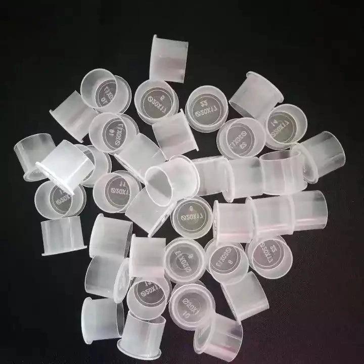 Collection of clear plastic ink cups on a dark background