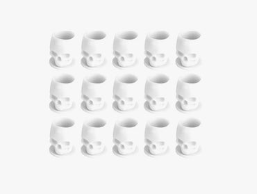 Set of white skull-shaped tattoo ink cups arranged in a grid on a white background