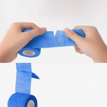 Hands tearing a roll of blue tattoo grip tape against a white background