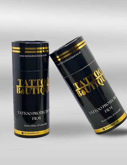 Two black cylindrical containers with gold accents labeled 'Tattoo Boutique' on a gray background.