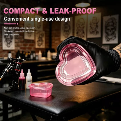 A SUPERAY pink rinse cup for tattoo workstation setups held by a black-gloved hand in a tattoo studio setting, with the text 'COMPACT & LEAK-PROOF' and 'Convenient single-use design' overlaid at the top.