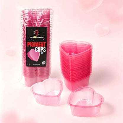 A pack Pink heart shaped tattoo rinse cups pack of 40 in pink, shown with a stack of filled cups and two empty cups in front, on a soft pink background.