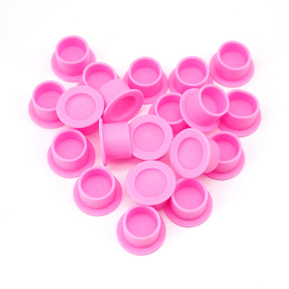 Pink Silicone Ink caps scattered on a white background