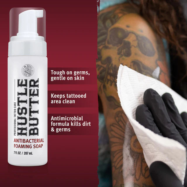 Hustle Butter antibacterial foaming soap bottle with a tattooed arm being cleaned.
