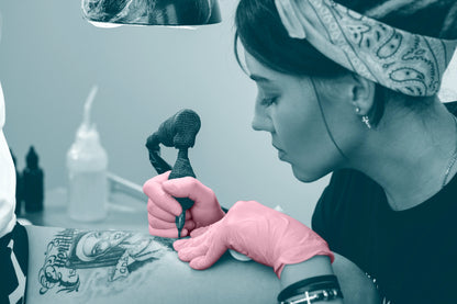 Tattoo artist wearing pink tattoo gloves 