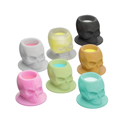 Set of colorful skull-shaped ink cups on a white background