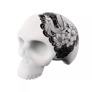 A 3D silicone skull training model for tattoo practice featuring a black and white floral and bird illustration printed on the side, shown against a plain white background.