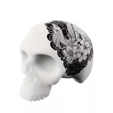 A 3D silicone skull training model for tattoo practice featuring a black and white floral and bird illustration printed on the side, shown against a plain white background.