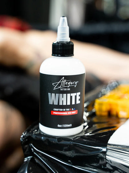 Bottle of Allegory Tattoo Ink White on a tattoo set up with blurred background