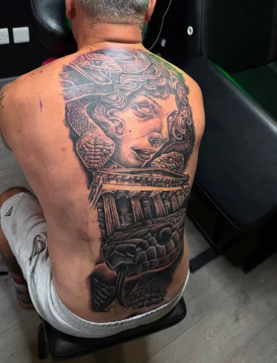 Person with a detailed tattoo on their back, featuring a classical design.