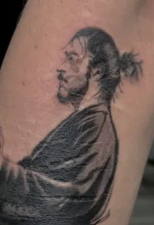 Tattoo of a person with a ponytail on a person's arm.