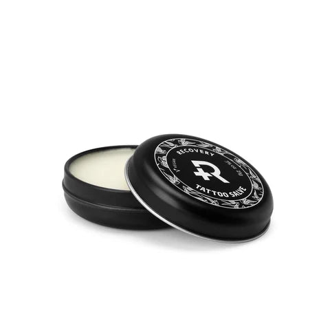 Black tin of tattoo salve with 'Recovery' branding on a white background