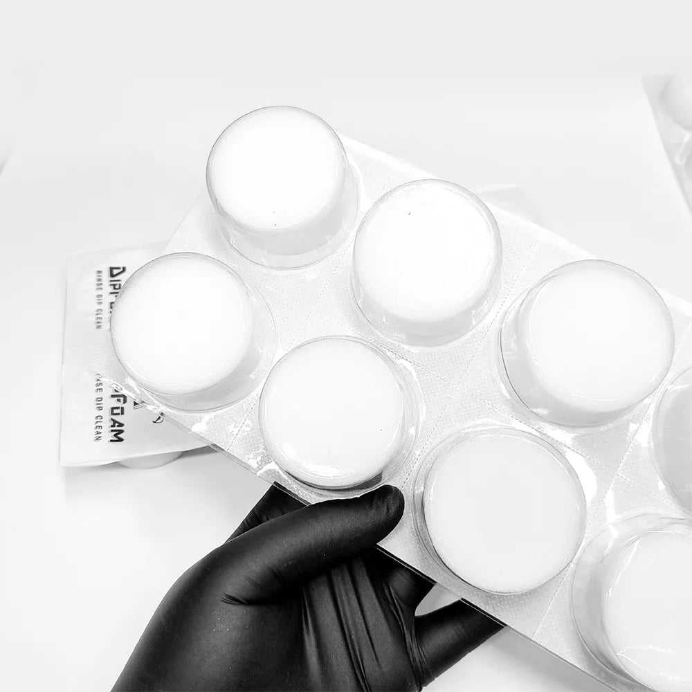 Hand holding a pack of Dip Foam needle cleaning cup